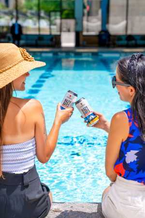 Two friends sip on Cowbell Brewing Co. beer at the Sheraton Centre Toronto pool