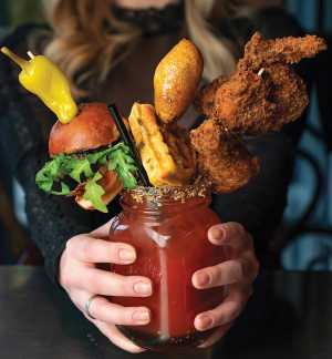 The history of the caesar cocktail | An over the top caesar stacked with a slider, a waffle and chicken wings