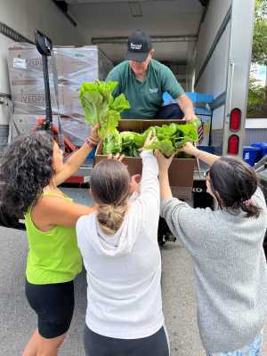 A group of Second Harvest volunteers unpacking lettuce from a truck