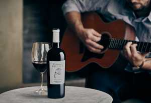 Celebrity wines | Someone playing guitar next to a bottle and glass of Z. Alexander Brown Uncaged Cabernet Sauvignon