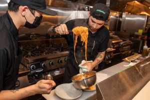 Two chefs serve spaghetti at the chef's counter at Occhiolino Toronto