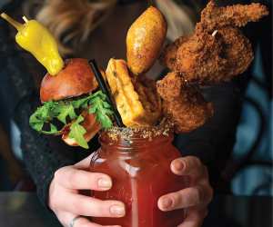 The history of the caesar cocktail |  An over the top caesar stacked with a slider, a waffle and chicken wings