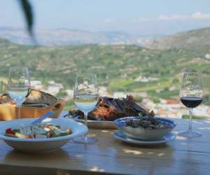 Greek wines | A table of food and wine overlooking Crete, Greece