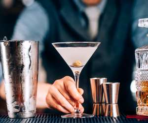 A bartender serves a martini over the bar