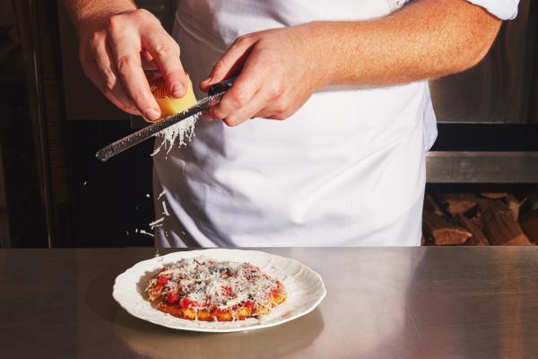 Q&A with Patrick Kriss of Alo, Alobar and Alder | Chef shreds cheese over an anchovy potato flatbread