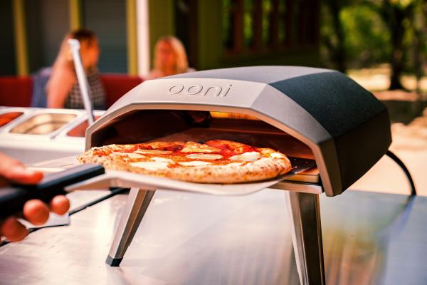 A freshly baked pizza coming out of an Ooni Koda 12 Oven
