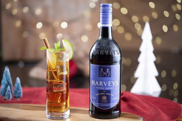 An orange cocktail beside a bottle of Harveys Bristol Sherry