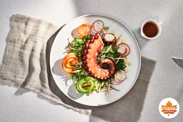 A maple glazed octopus on a plate with salad