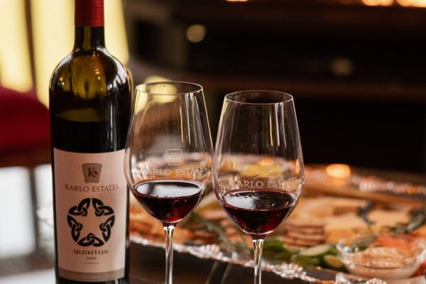 Ontario Wine Awards | A bottle of Karlo Cellars wine and two glasses by the fire