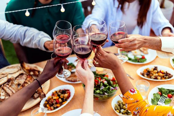 Wine pairings | Friends cheers red wine glasses over a table of food