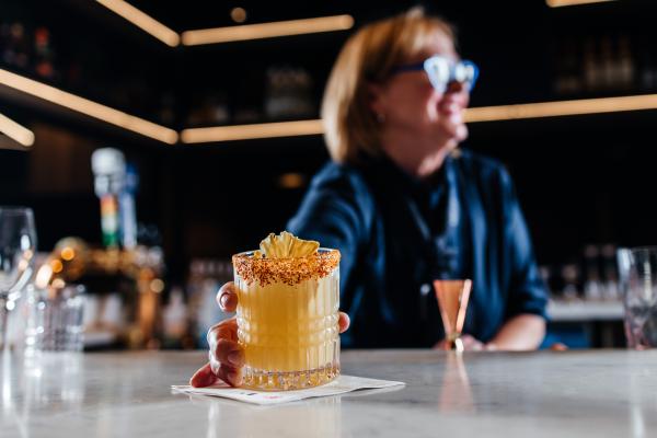 A bartender serves a cocktail inside the Aspire | Air Canada Café at Billy Bishop Toronto City Airport