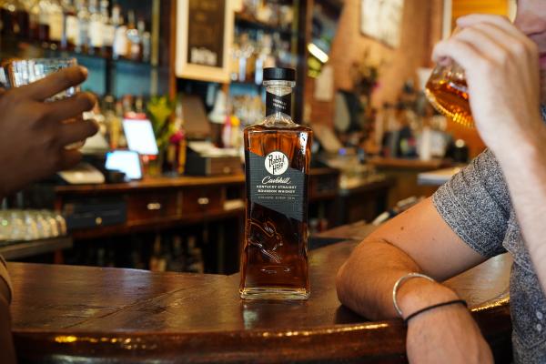 Rabbit Hole Kentucky bourbon on the bar with two people drinking Rabbit Hole Kentucky bourbon on the bar with two people drinking