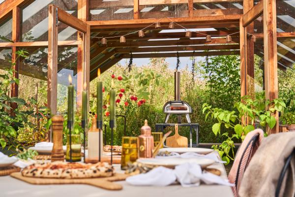 The Ooni Karu 12G pizza oven in a garden behind a set table with pizzas