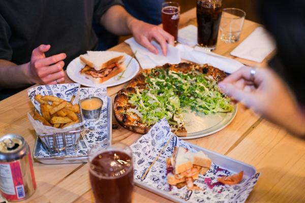 Left Field Brewery, Liberty Village, Toronto | Hands picking over an assortment of dishes at Left Field Brewery