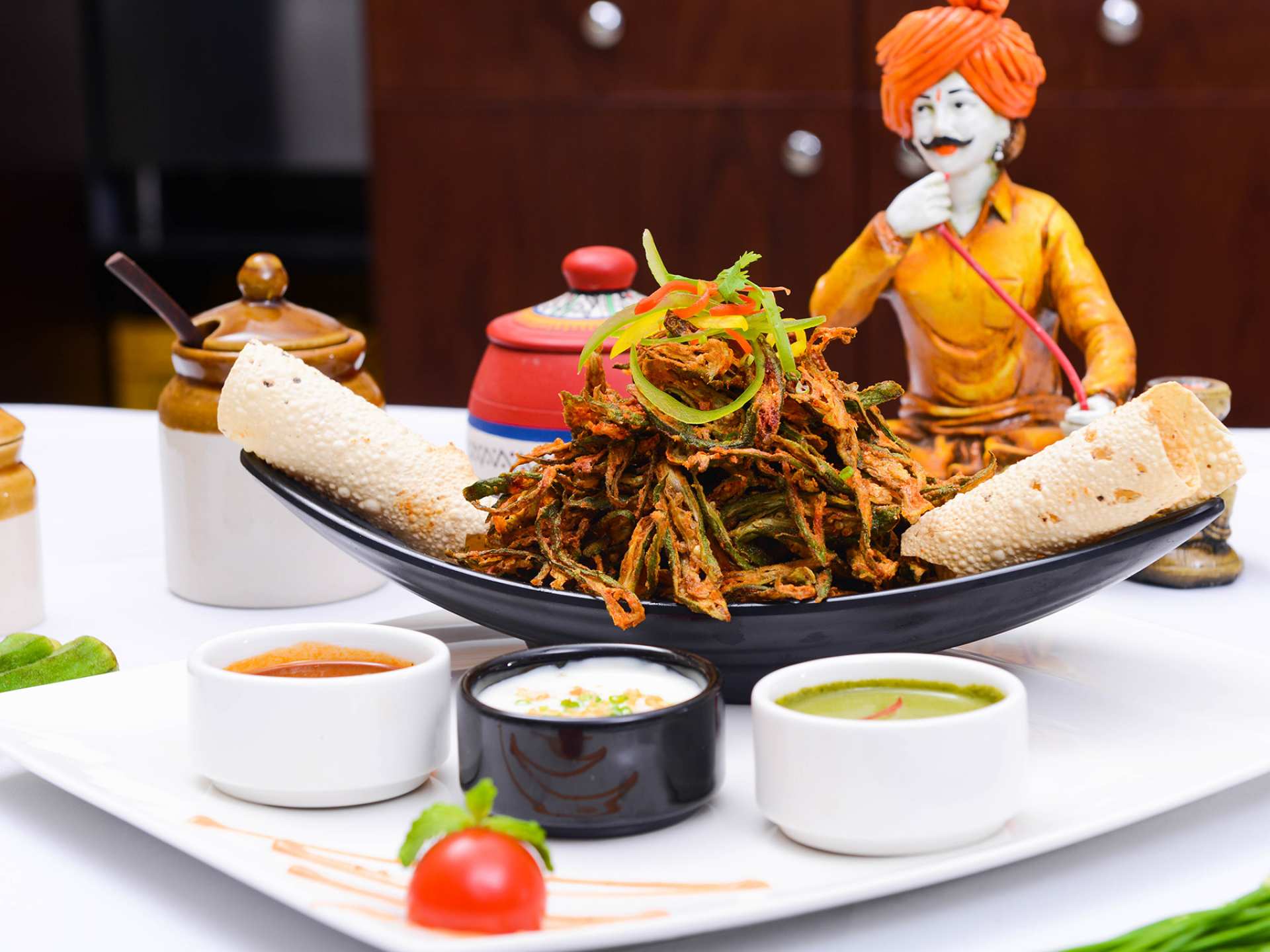 Khau Gully vegan menu | Fried okra stacked on a plate with a figurine in the background