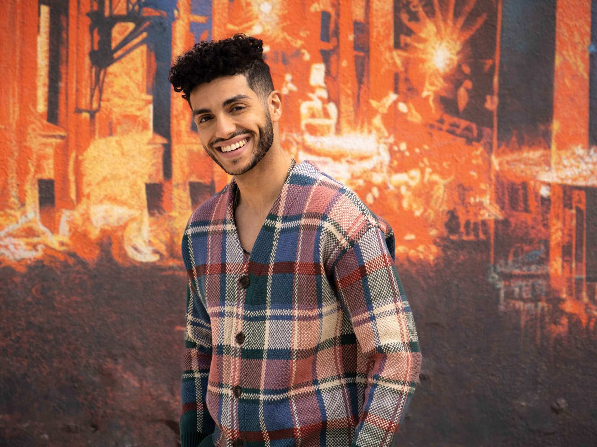 Vegan food in Toronto | Mena Massoud smiling in front of a colourful wall