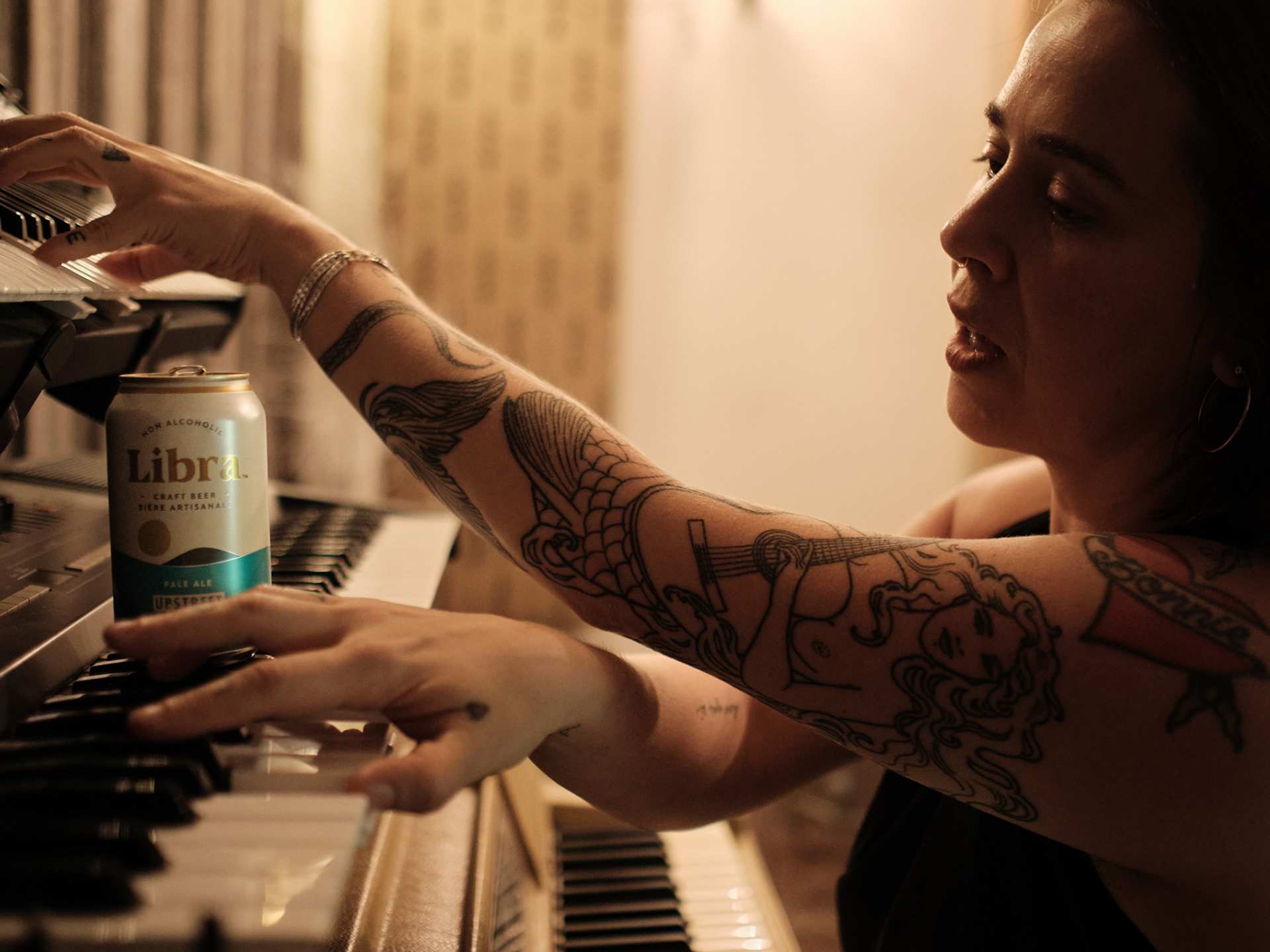 Serena Ryder at her piano with a can of Libra non-alcoholic beer