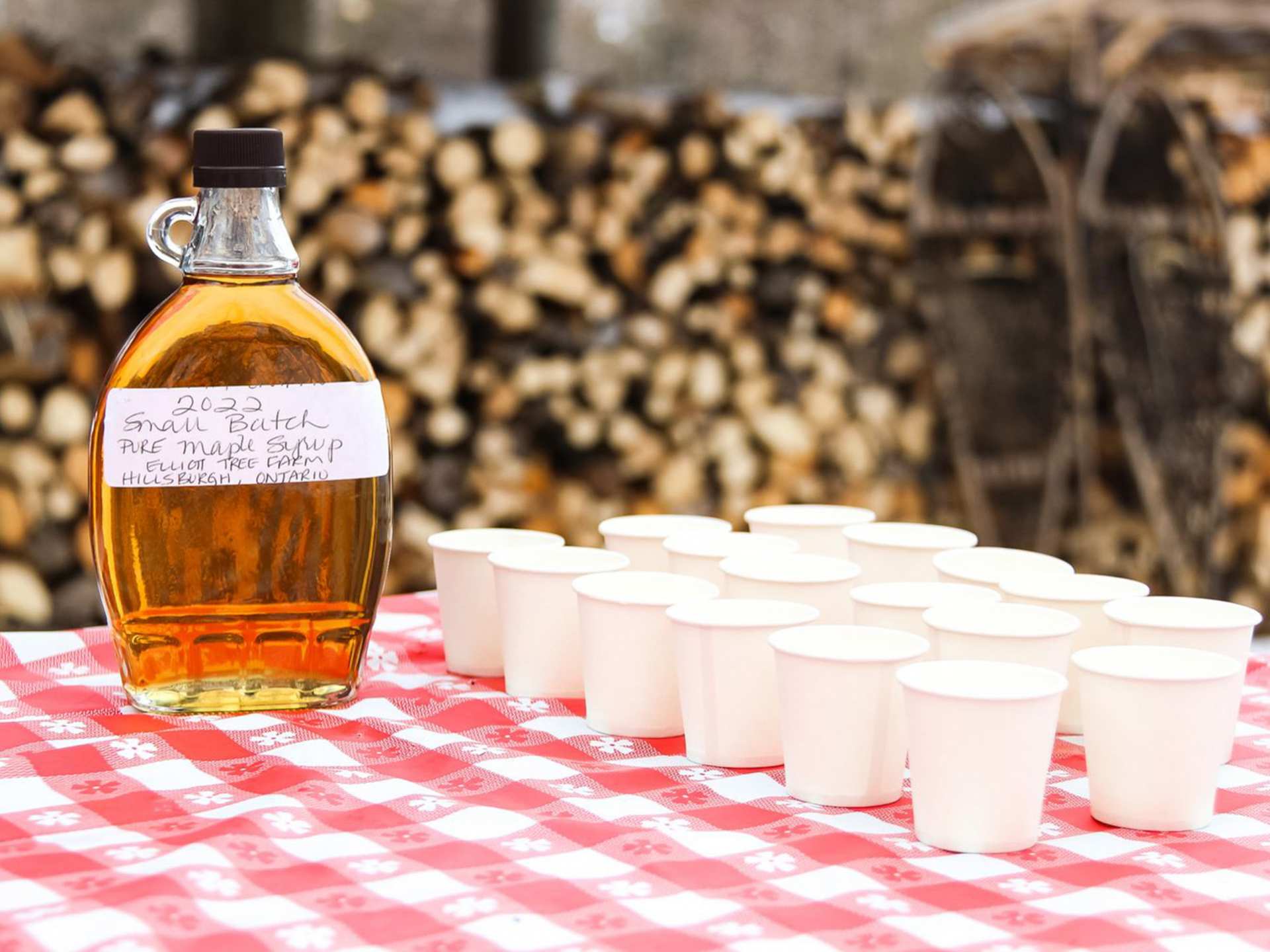 Rural Route Tour Co. maple syrup farm tour | A bottle of Elliott Tree Farm maple syrup with sample cups on a table