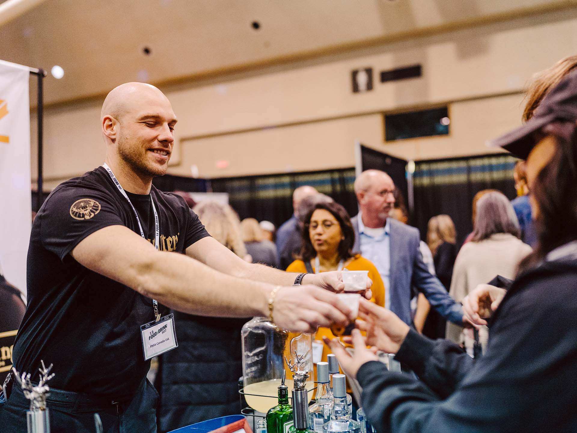A vendor sharing sample with an attendee at the T.O. Food and Drink Fest