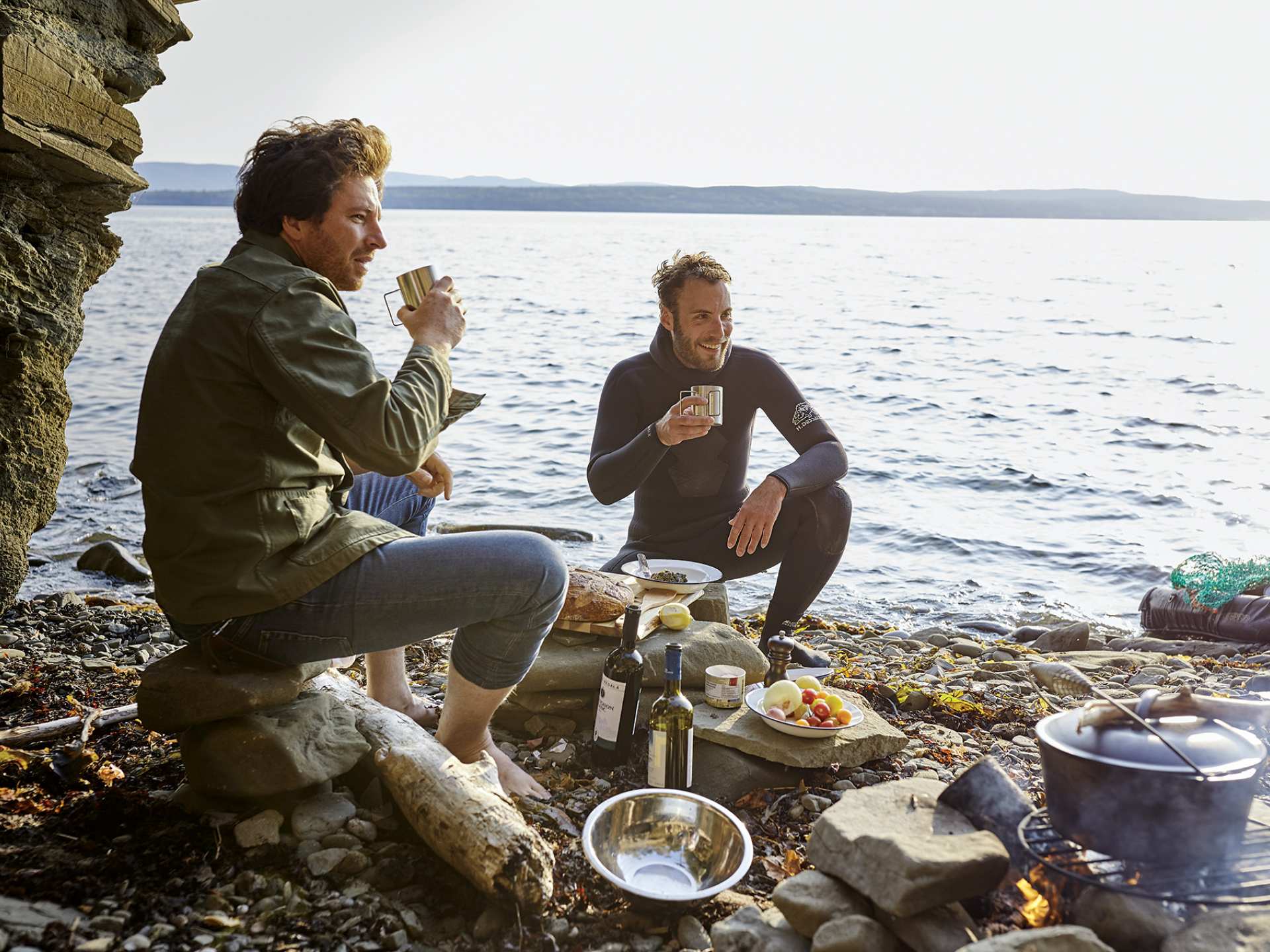 Two men enjoying a seafood boil and wine by the ocean