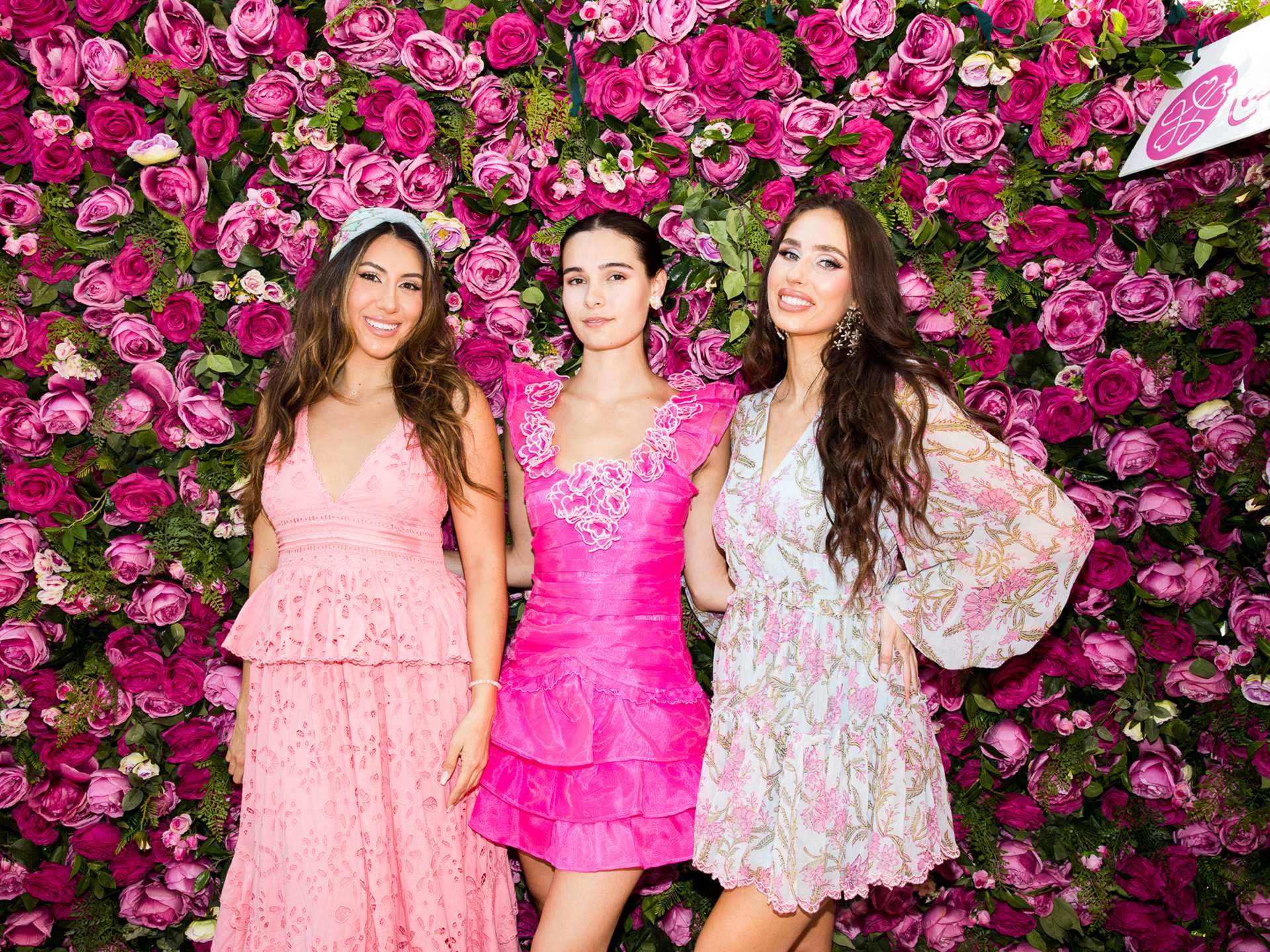 Three people in front of a flower wall at the Rosé Picnic at Hotel X