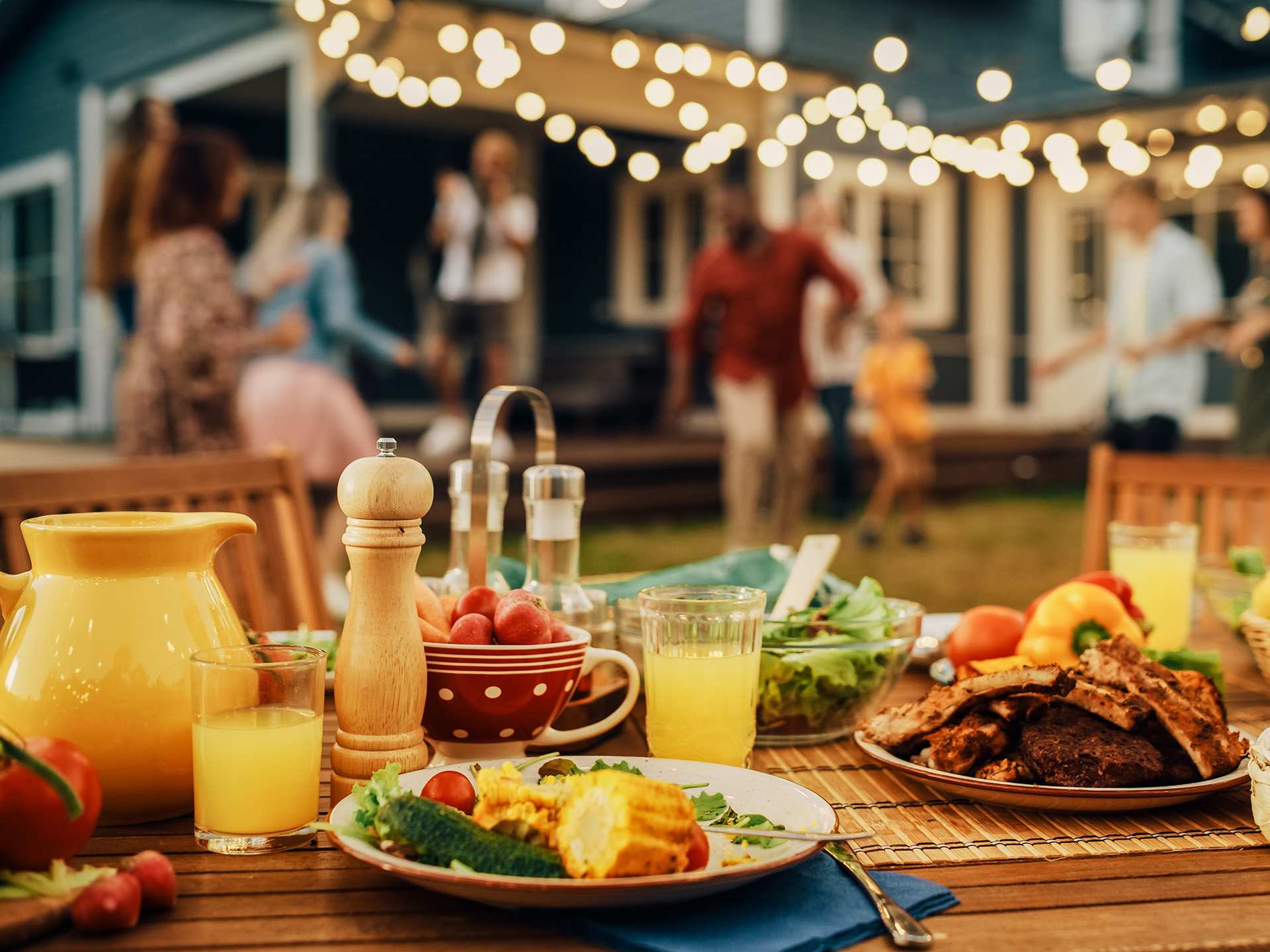 A summer party spread with juice, different plates and guests enjoying themselves in the background