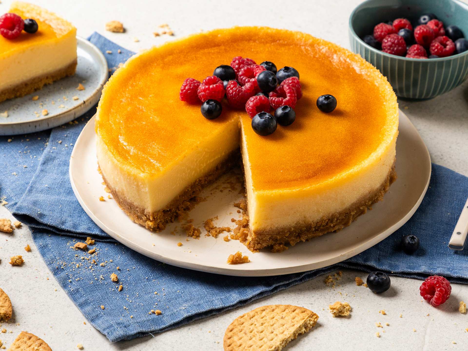 A cheesecake adorned with fresh fruit and with graham crackers