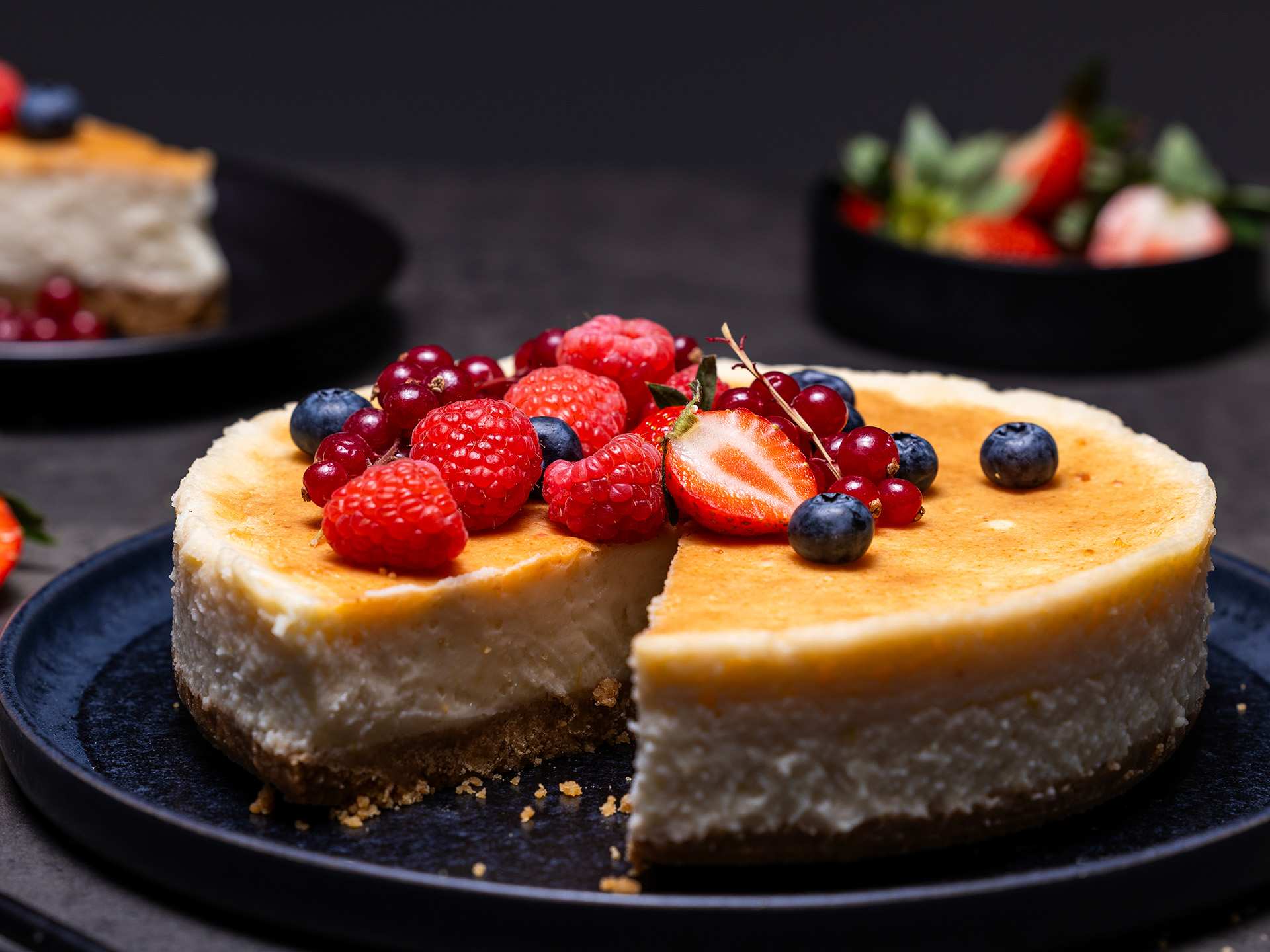 A dairy-free cheesecake topped with fresh strawberries and blueberries