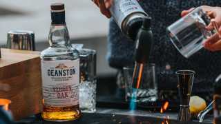 Deanston smoked old fashioned recipe | a bartender using a blow torch on a Spirits with Smoke cocktail smoking board