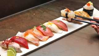 The best sushi in Toronto | Chopsticks picking up a piece of sushi from a plate of assorted nigiri sushi at JaBistro