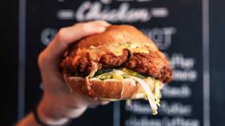 The best fried chicken sandwiches in Toronto | Someone holds up a sandwich from Knuckle Sandwich