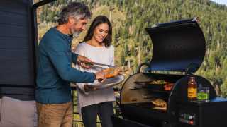 A couple cooks salmon on a Traeger grill