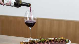 Sara wine pairing | A glass of red wine is paired with NY Striploin at Sara