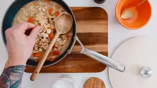 Kilne Everything Pan with pasta and a person sprinkling cheese on top