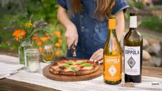 Coppola wines and a woman slicing a freshly baked pizza