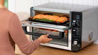 Someone taking salmon out of the Ninja 12-in-1 Double Oven