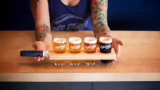 Toronto bottle shops and alcohol stores | A person holding a flight of three beers at Left Field Brewery in Toronto