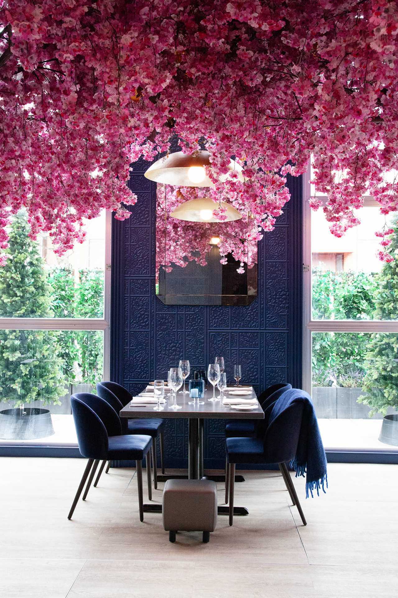 Via Allegro Ristorante | A table under pink flowers inside the glass-enclosed heated patio