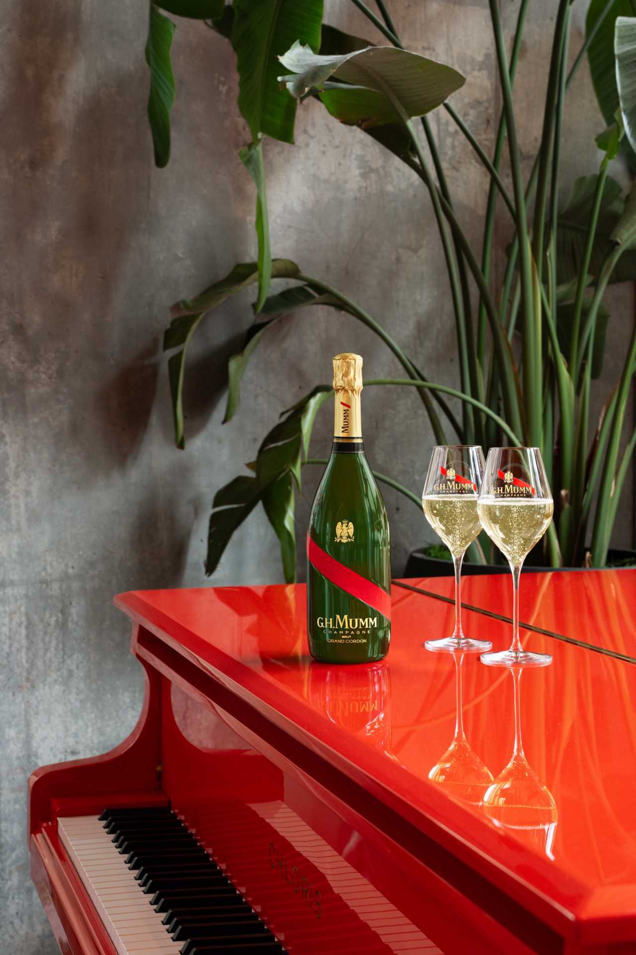 G.H.Mumm | Two glasses of champagne and a bottle of G.H.Mumm sits on a red piano