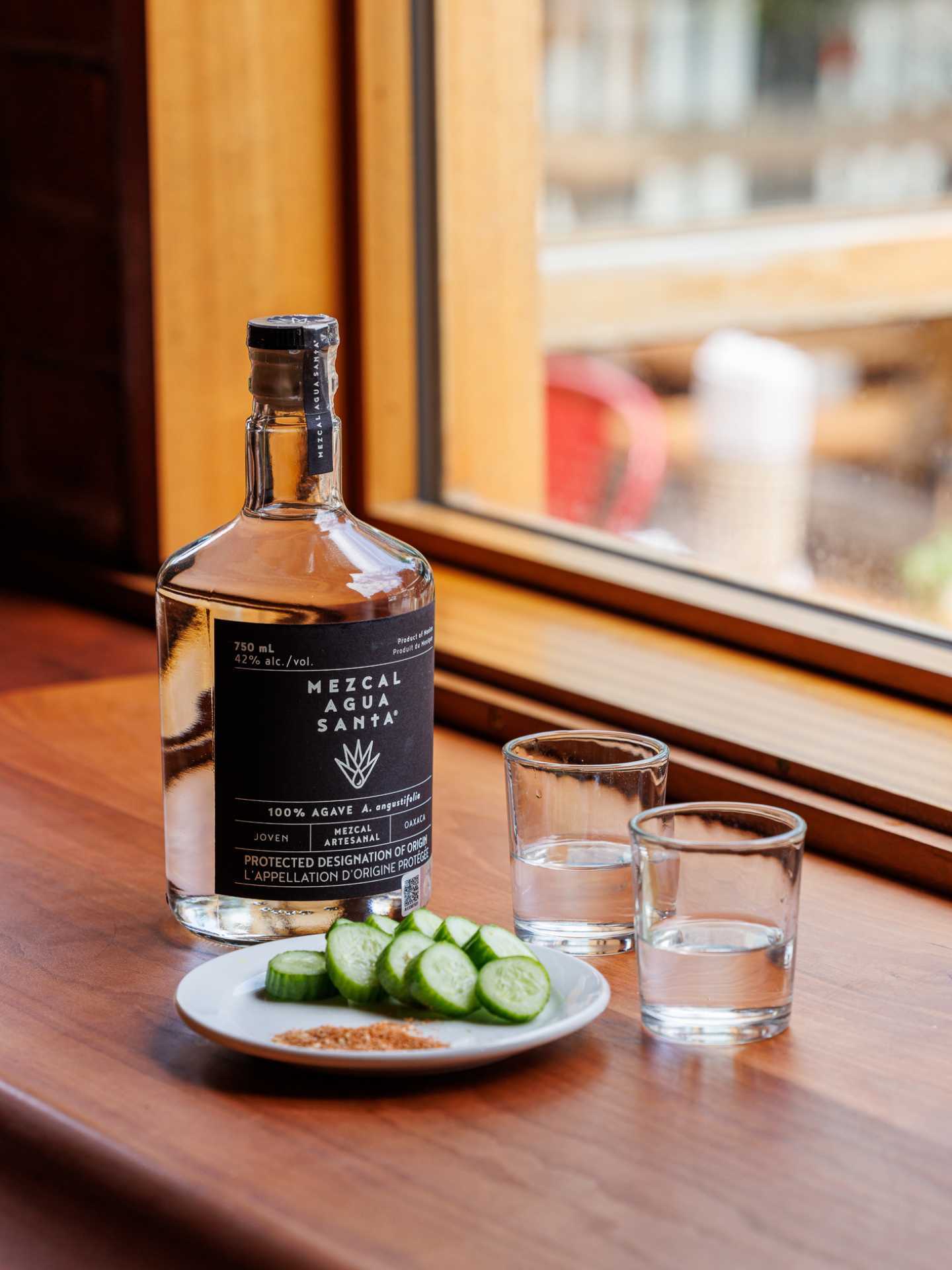 Tequila and mezcal | A bottle of mezcal on a table with cucumbers and rimming salt