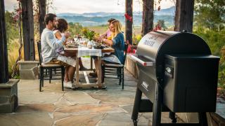 A group of people dine next to a Traeger grill