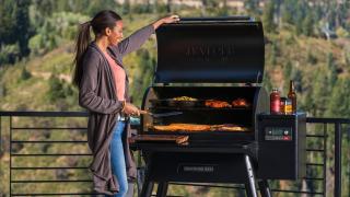 A woman cooks over pure wood on a Traeger grill