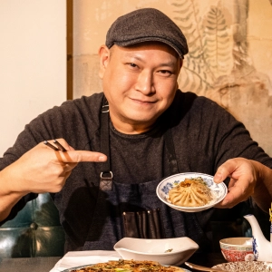 Chef Nick Liu smiling and pointing at dumplings