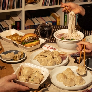 Noodles, burgers, dumplings and other food items on a dining table