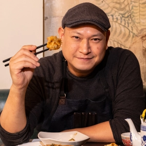 Chef Nick Liu holding a dumpling between two chopsticks