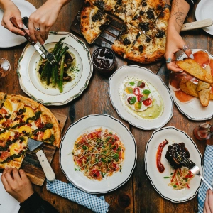 Plates of pizza and ceviche spread out on a tabletop
