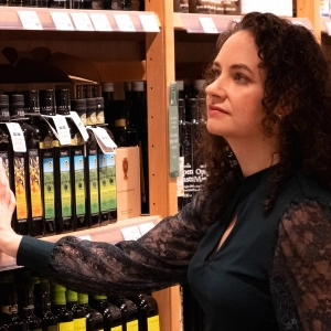 A woman looking at bottles of olive oil on shelves at Eataly