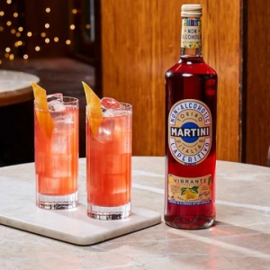 A bottle of Martini Fiero with two orange cocktails on a table