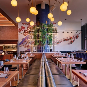 A dining room with chairs and tables and colourful vibrant art in the background