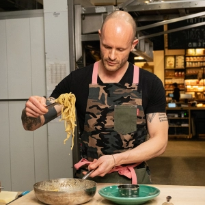 Ruben Rapetti holding a forkful of spaghetti wearing a camo apron